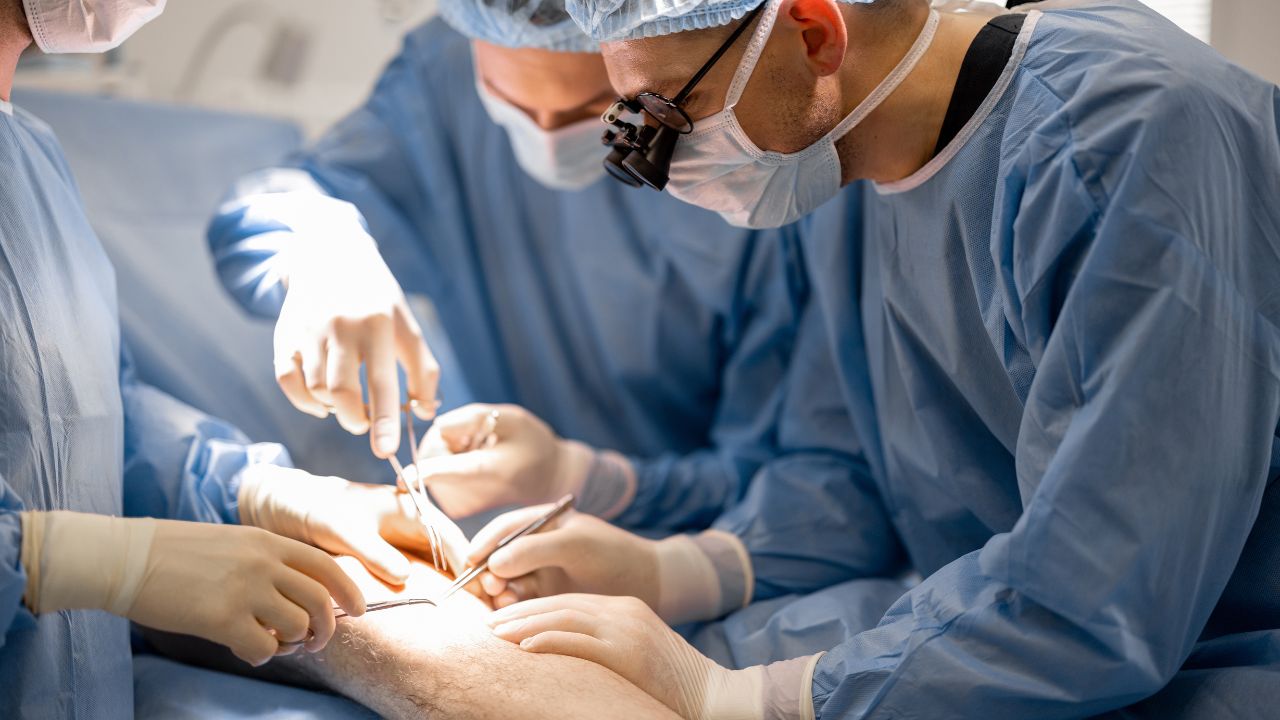 surgeons performing surgical operation on a patient’s knee surgeons performing surgical operation on a patient's knee
