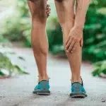Leg Pain Close-up of a runner holding their calf, representing an athletic injury, muscle strain, or chronic leg pain that requires treatment.