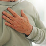 Heart attack, cardiology and person hand on chest with pain, sick and cardiovascular closeup. Indigestion, heartburn and health with wellness, elderly care with medical issue and hypertension hearthburn