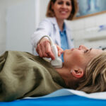 Female patient undergoing thyroid ultrasound examination Medical illustration showing plaque buildup in the neck to explain carotid artery disease.