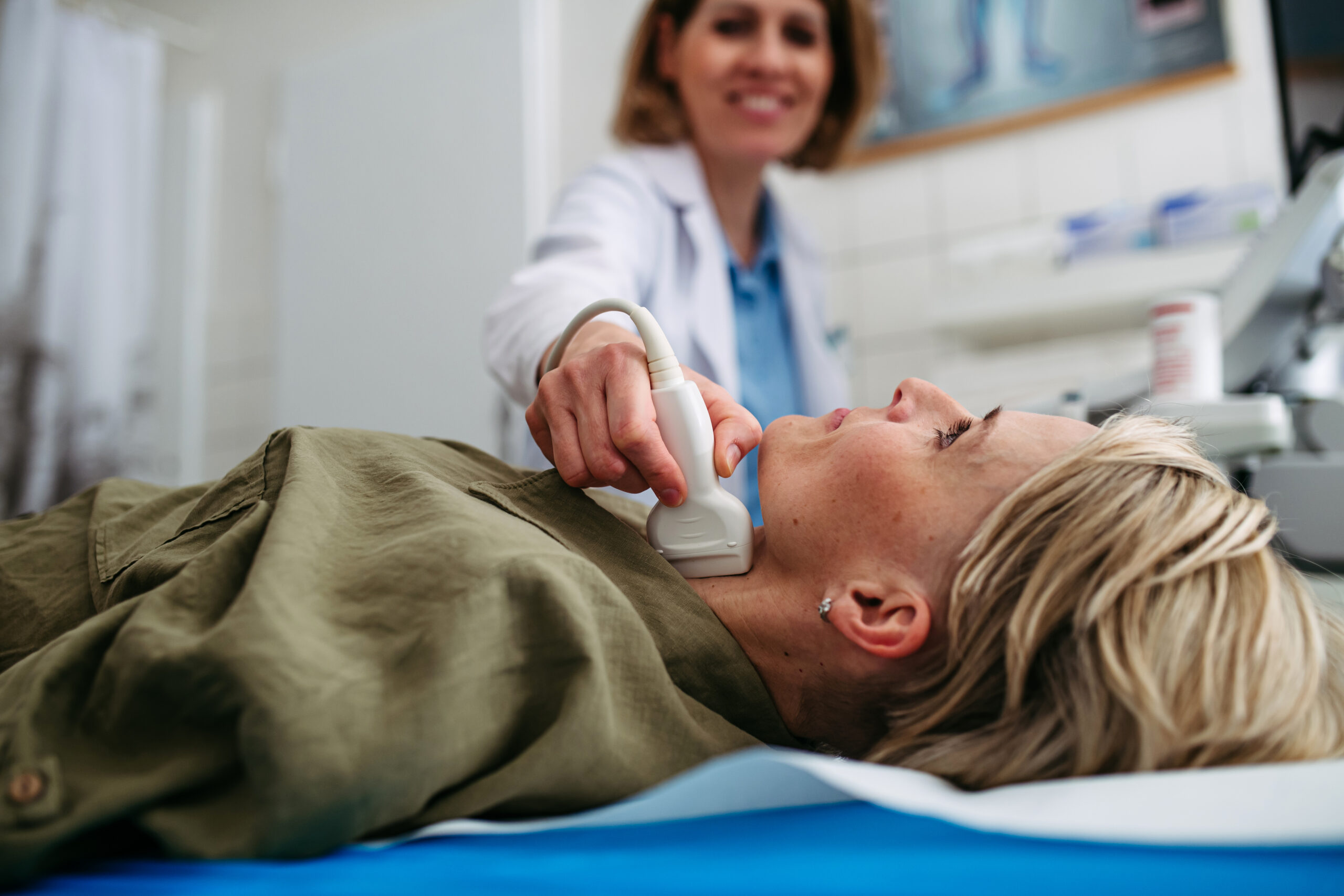 Female patient undergoing thyroid ultrasound examination Medical illustration showing plaque buildup in the neck to explain carotid artery disease.